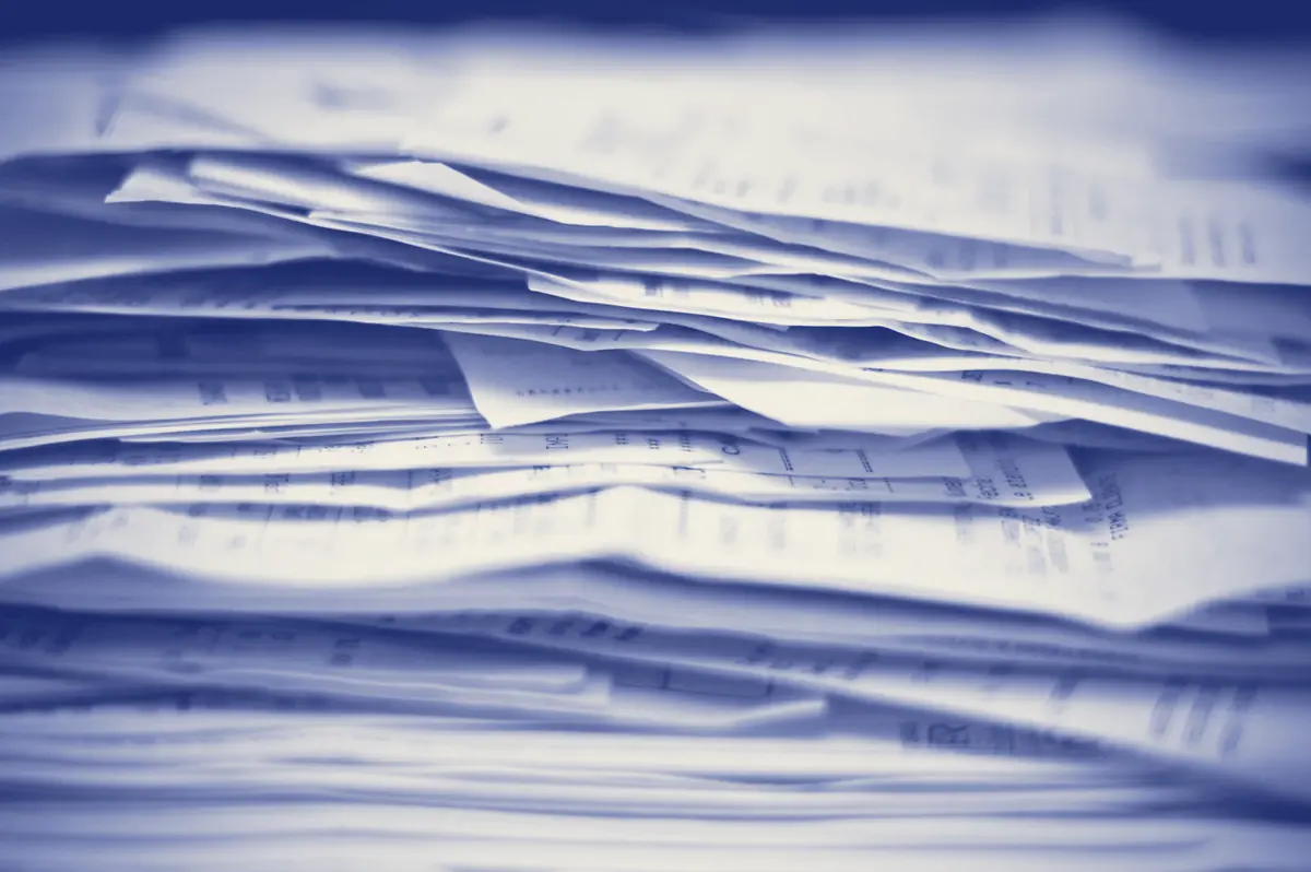 A tall stack of paper invoices and receipts